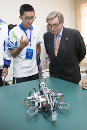 A student explains to Club Chairman T. Brian Stevenson (right) how the remote control robot works during a visit to Deyang HKJC No. 5 Middle School.