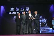 Dr Eric K C Li, Steward of The Hong Kong Jockey Club, presents the trophy to Mr Wilson Woo Ka Wah, owner of Champion Stayer Helene Super Star, and his son.