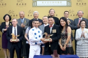 Executive Director of the Oriental Watch Holdings Limited Mr Alain Lam Hing Lun, accompanied by his wife, presents a souvenir to jockey Joao Moreira.