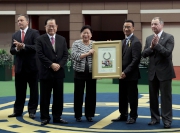 Owners  Dr. Chang Fuk-to and his wife Maria Chang Lee Ming-shum present  a framed <em>Lucky Nine</em> horseshoe to the  Hong Kong Jockey Club Steward Michael Lee.
