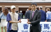 Commissioner for Sports Yeung Tak-keung (right) presents the Best Turned Out Horse award to the winning stables assistant of Invincible Dragon (left). 