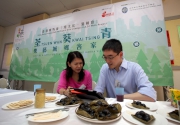 The Cluba?s Executive Director, Charities, Douglas So (right) and HULU Culture Executive Director Iman Fok (left) sample some traditional snacks of Lo Wai Village while browsing the iTour app.
